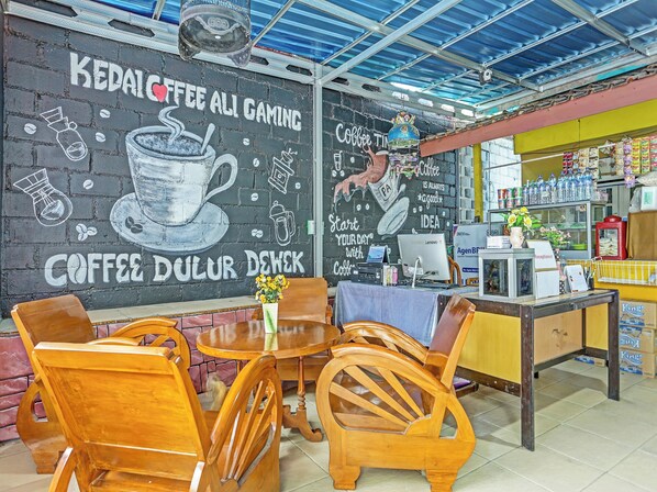 A coffee shop interior with a chalkboard wall, wooden furniture, and a counter with various items.