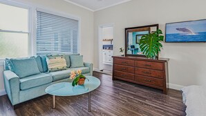 A living room with a sofa, coffee table, and a wooden cabinet. - Newly Renovated Modern Cottage: Walk into Historic Wailuku Town! (Wailuku)