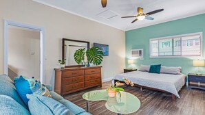A modern bedroom with a bed, a nightstand, a dresser, a sofa, and a small table with plants. - Newly Renovated Modern Cottage: Walk into Historic Wailuku Town! (Wailuku)