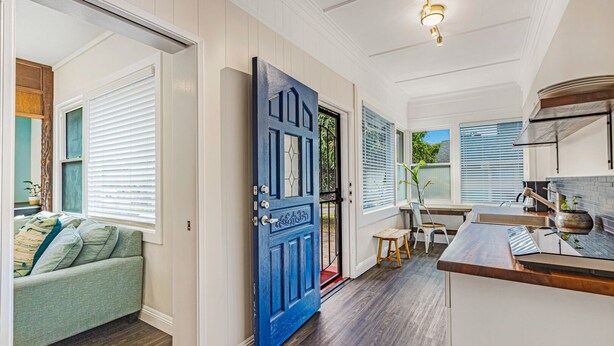 A modern kitchen with a wooden countertop, a dining area with a table and chairs, and a blue door with decorative glass panels. - Newly Renovated Modern Cottage: Walk into Historic Wailuku Town! (Wailuku)