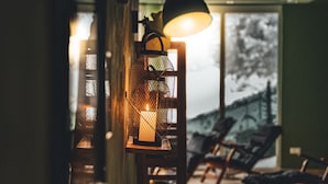 Una habitación con piso de madera, un ventanal grande y una lámpara colgante.