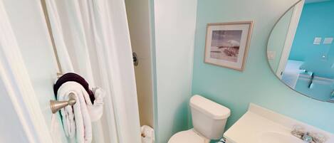 A bathroom with a toilet, sink, and a framed picture on the wall.