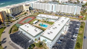 Vista aérea de um hotel com vários edifícios, uma piscina e estacionamento.