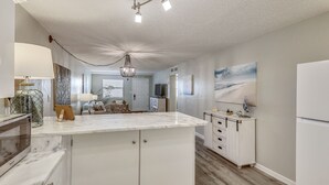 Une cuisine moderne avec un îlot en marbre, des meubles blancs et un lustre.