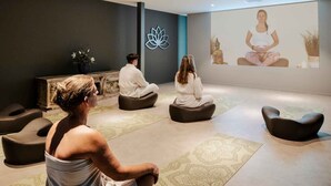 A meditation room with a lotus symbol on the wall, a Buddha statue, and a person meditating.