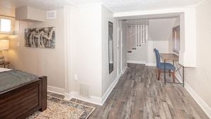 A bedroom with a bed, a desk, and a chair. There is a staircase leading to another room. - Cozy Carriage House | Walk to UNC | + Free Bikes (Greeley)