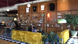 A library with bookshelves, a yellow sofa, and a checkered floor. - Cozy Retreat | Walk to UNC | FREE Cruiser Bikes (Greeley)