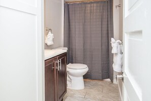 A small bathroom with a toilet, a sink, and a shower curtain. - Cozy Retreat | Walk to UNC | FREE Cruiser Bikes (Greeley)