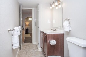 A modern bathroom with a wooden vanity, a large mirror, and a toilet. - Cozy Retreat | Walk to UNC | FREE Cruiser Bikes (Greeley)