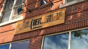 Un rètol de fusta amb la inscripció 'DR. BER. SHOP' en un edifici de maó.