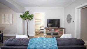 A living room with a sofa, a coffee table, a TV, and a plant. - Couple’s Getaway | Walk to UNC |FREE Cruiser Bikes (Greeley)