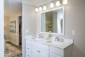 A bathroom with two sinks, a large mirror, and a light fixture above the mirror.