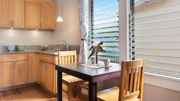 A kitchen with wooden cabinets, a granite countertop, a sink, and a dining table with chairs.
