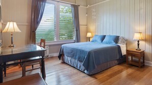 A bedroom with a bed, bedside tables, a desk, and a chair.