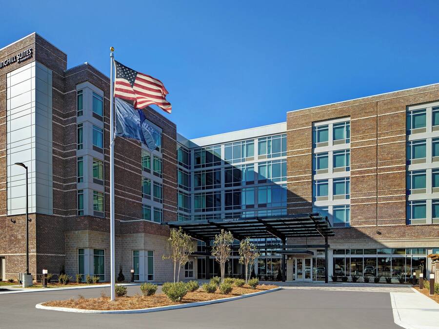 A hotel with a brick facade, large windows, and an American flag.