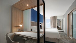 Une chambre d’hôtel avec un grand lit, un bureau, une chaise et un miroir.
