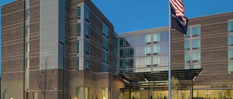 A modern hotel with a brick facade, large windows, and an American flag.