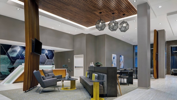 A modern lobby with a reception desk, seating area, and a staircase. - SpringHill Suites by Marriott Franklin Cool Springs (Franklin)