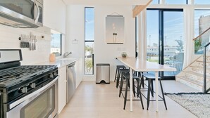 Une cuisine moderne équipée d’une cuisinière, d’un four à micro-ondes et d’un ensemble de couteaux. Un coin repas avec une table et des chaises est également disponible.