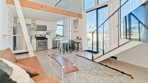 Une cuisine moderne dotée d’un îlot central, d’un coin repas avec des tabourets de bar et d’un escalier menant à un niveau supérieur.
