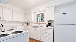 A modern kitchen with white cabinets, a stove, a sink, and a refrigerator. - Gorgeous Hideout Near Old Town – Free Bikes!! (Fort Collins)