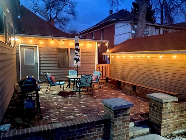 Enjoy a serene outdoor retreat with a central table and four chairs, surrounded by a beautifully maintained patio.