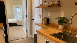 A modern kitchen with a wooden countertop, stainless steel sink, and a potted plant. - Gorgeous Guest Suite. Walk to Old Town & CSU! (Fort Collins)