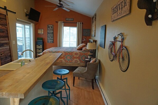 Una habitación acogedora con una cama, una mesa de madera, un lavamanos y una bicicleta colgada en la pared.