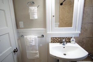A bathroom with a white sink, a mirror, and two towels hanging on the wall. - Beautiful Bungalow Next to UNC-FREE Cruiser Bikes! (Greeley)