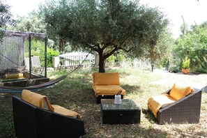 An outdoor seating area with wicker furniture and a hammock. - Vacation rental house with pool PUGET LS2-356 (Puget)