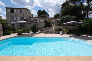 A swimming pool with two umbrellas, a stone staircase, and a building with multiple windows. - Vacation rental house with pool PUGET LS2-356 (Puget)