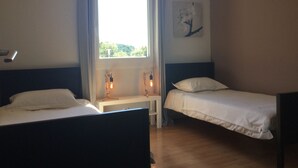 A bedroom with two beds, a window with curtains, a bedside table with a lamp, and a painting on the wall. - Vacation rental house with pool PUGET LS2-356 (Puget)