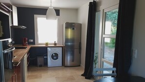 A compact kitchen with a washing machine, a refrigerator, and a window with curtains. - Vacation rental house with pool PUGET LS2-356 (Puget)