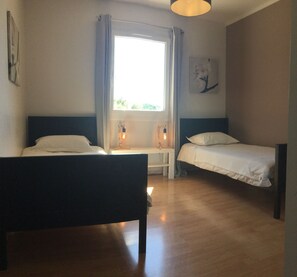 A room with two beds, a window with curtains, a bedside table with a lamp, and a painting on the wall. - Vacation rental house with pool PUGET LS2-356 (Puget)