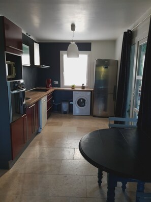A compact kitchen with a built-in oven, microwave, and a washing machine. There's a window providing natural light and a view of the outdoors. - Vacation rental house with pool PUGET LS2-356 (Puget)
