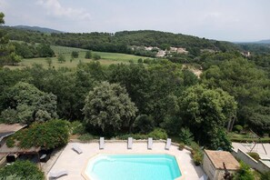 A pool area with lounge chairs, surrounded by lush greenery and a view of a hilly landscape. - Vacation rental house with pool PUGET LS2-356 (Puget)