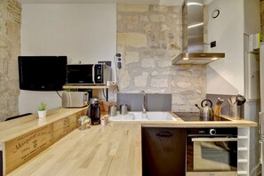 Uma cozinha moderna com parede de pedra, eletrodomésticos de aço inoxidável e bancadas de madeira.