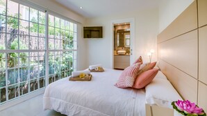 A bedroom with a large window, a bed with pillows, a bedside table, and a mirror. - Luxurious house near sea Barcares Nou Alcudia (Alcúdia)