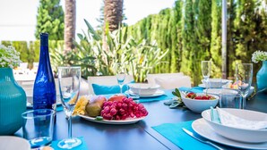 A table set for a meal with a view of a lush garden and tall trees. - Luxurious house near sea Barcares Nou Alcudia (Alcúdia)