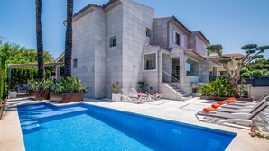 A modern building with a swimming pool, outdoor seating, and palm trees. - Luxurious house near sea Barcares Nou Alcudia (Alcúdia)