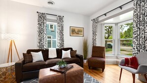A living room with a brown sofa, a patterned armchair, a grey armchair, a wooden coffee table, and a floor lamp. - Lola House! Cozy comfort, Prime Old Town Location (Fort Collins)