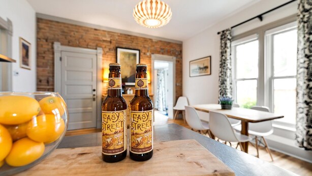 A modern kitchen with a brick wall, a wooden cutting board with two bottles of Easy Street beer, and a bowl of lemons. - Lola House! Cozy comfort, Prime Old Town Location (Fort Collins)