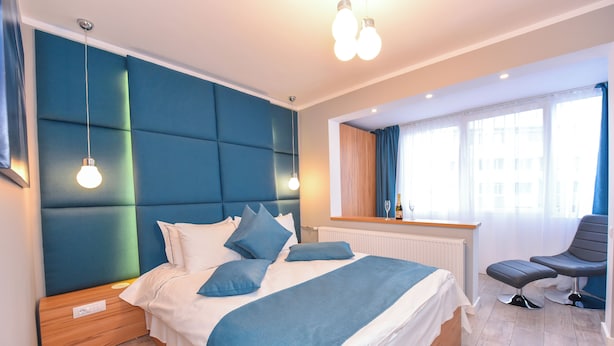 Een moderne slaapkamer met een groot bed, een nachtkastje, een stoel en een raam met gordijnen.