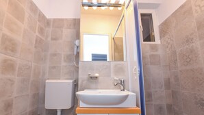 Een badkamer met een wit wastafelmeubel, een toilet en een douchegedeelte.