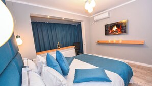 Een moderne slaapkamer met een groot bed, een bureau en een open haard aan de muur.