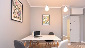 Een moderne kamer met een witte tafel, twee stoelen, een laptop en twee lichtbronnen.