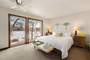 A bedroom with a large bed, two bedside tables, a bench, and a ceiling fan. - Peaceful Retro Retreat w/Stunning Lake Views!! (Fort Collins)