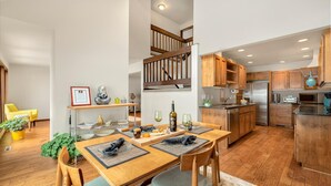 Una cocina moderna con armarios de madera, un refrigerador de acero inoxidable y un comedor con mesa y sillas de madera.