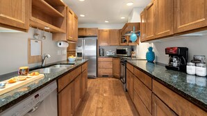 Una cocina moderna con armarios de madera, electrodomésticos de acero inoxidable, una encimera de granito y lavavajillas.