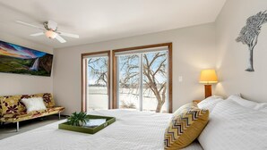Un dormitorio con cama, una bandeja verde, sofá, lámpara y un cuadro.